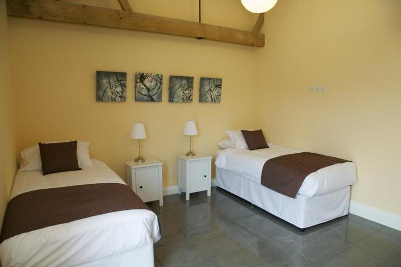 a bedroom with two beds and two lamps on tables at Pheasants Roost at Tove Valley Cottages in Towcester