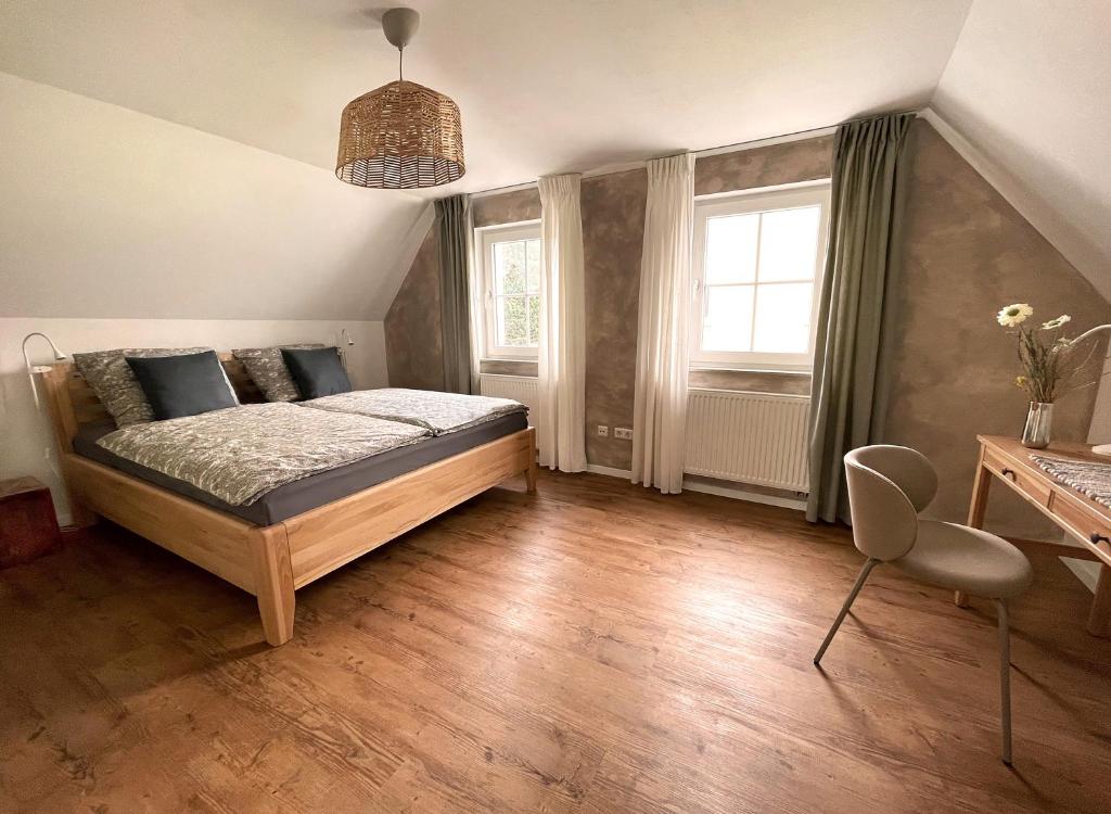 a bedroom with a bed and a desk and two windows at Haus Silberberg in Haslach im Kinzigtal