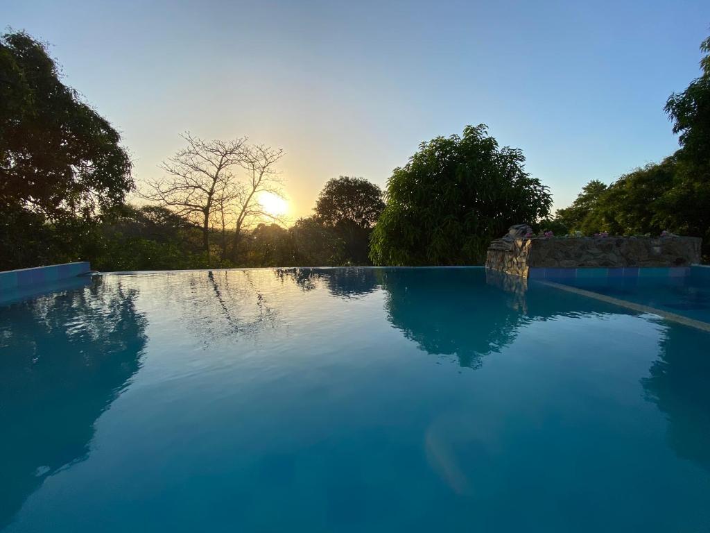 a large blue swimming pool with the sunset in the background at AFRA Reserva Natural in Santa Marta