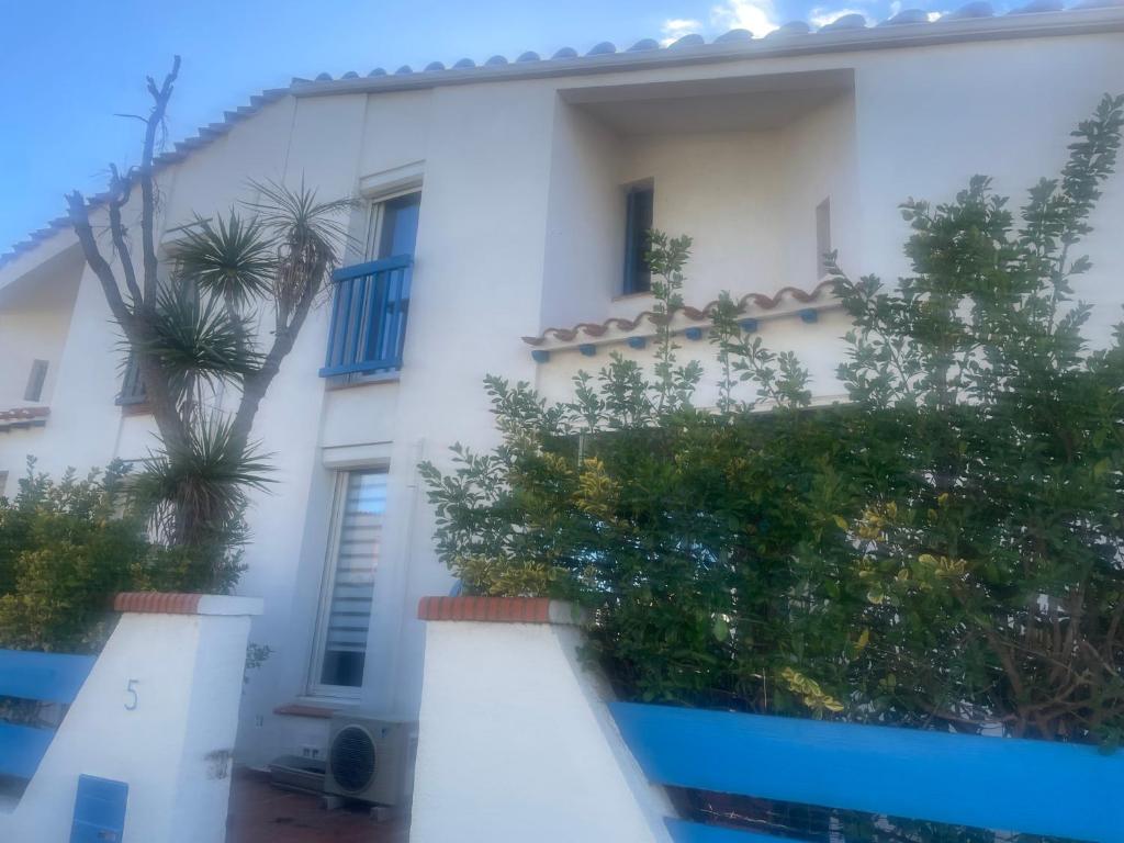 une maison blanche avec des palmiers devant dans l'établissement VILLA CANET EN ROUSSILLON, à Canet