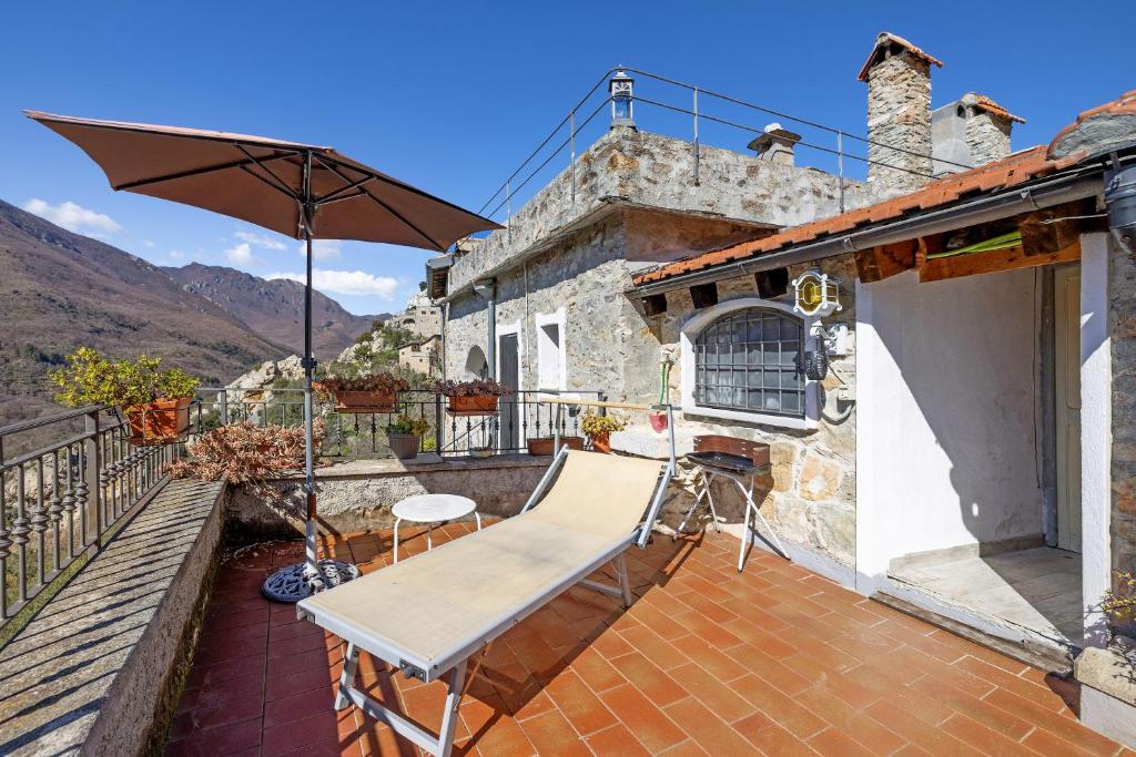 a patio with an umbrella and a bench on a balcony at La Dimora del Tempo Perduto in Castelvecchio di Rocca Barbena