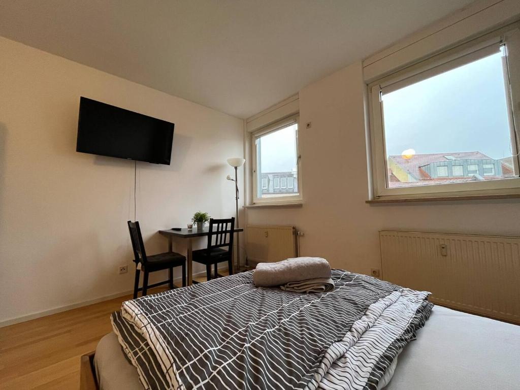 a bedroom with a bed with a television and a table at Simplex Apartments Am Ludwigsplatz in Karlsruhe