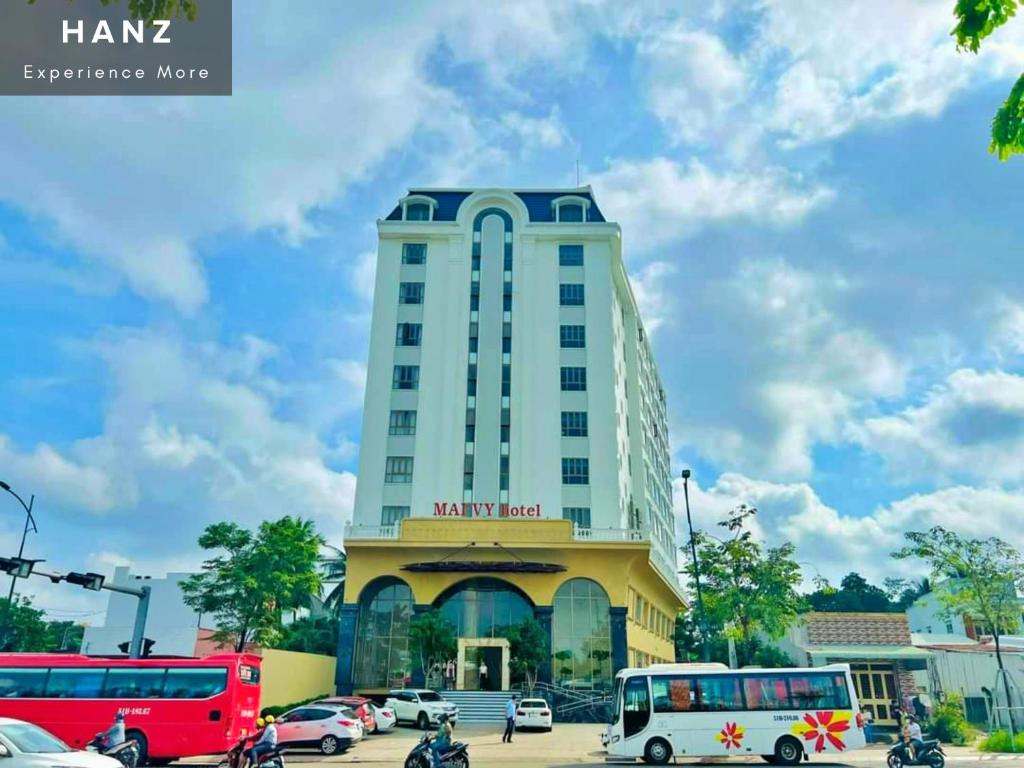 a tall building with cars parked in a parking lot at HANZ Premium Mai Vy Hotel in Tây Ninh