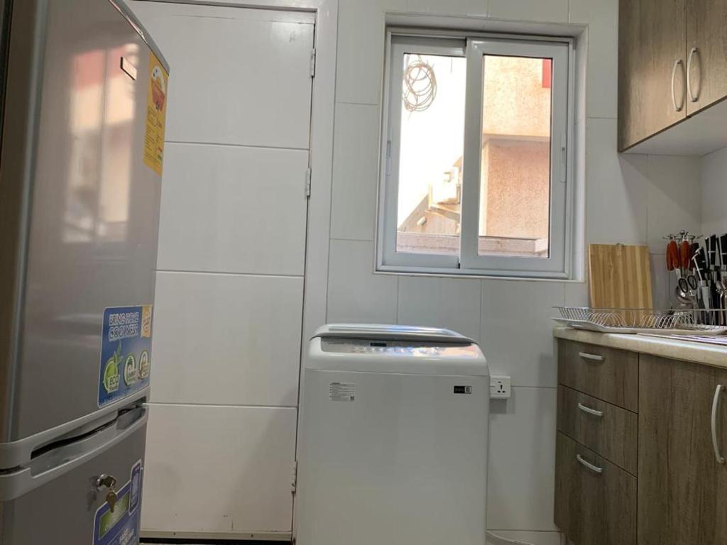 una nevera blanca en una cocina con ventana en The Greens Estate, en Madina