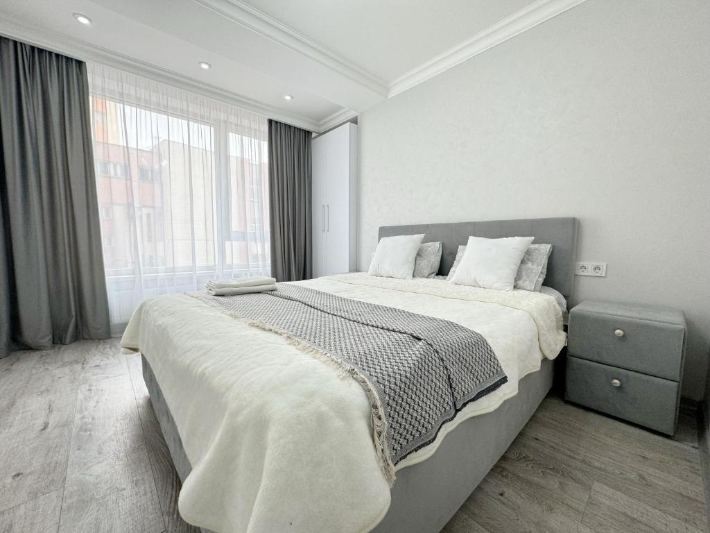 a bedroom with a large bed and a large window at Bella White Apartment in Chişinău