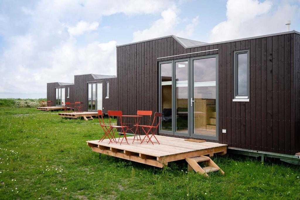 ein schwarzes Haus mit roten Stühlen auf einer Terrasse in der Unterkunft Tiny House Nature 1 Innenlage - Green Tiny Village Harlesiel in Carolinensiel