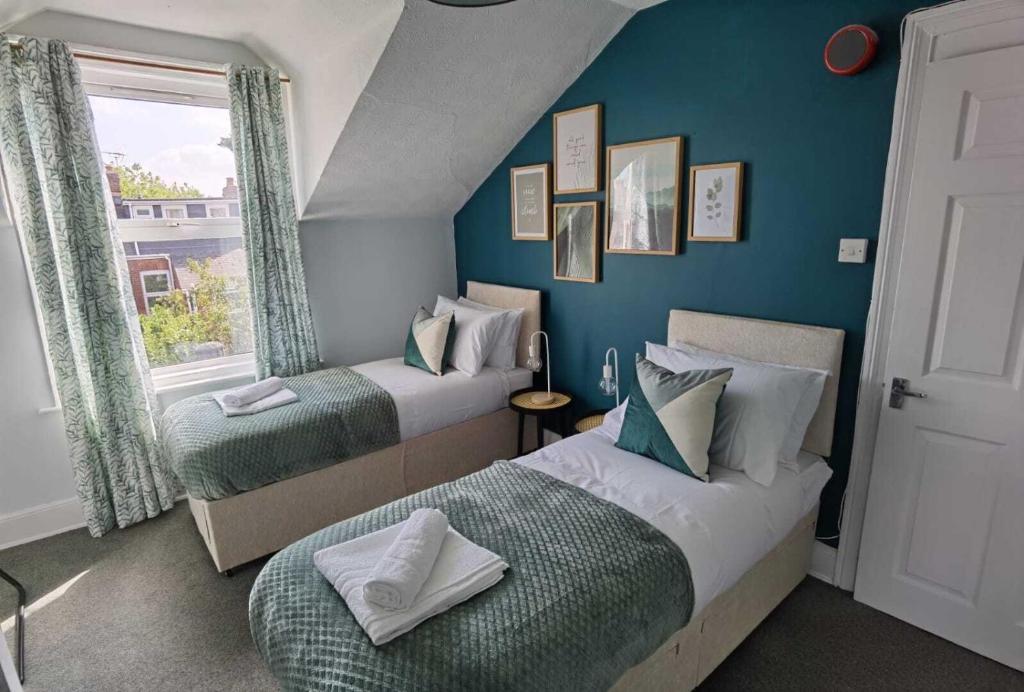 Duas camas num quarto com paredes azuis e uma janela em OPP Exeter RRF&T - Cosy 1 bed with parking BIG SAVINGS booking 7 nights or more! em Exeter