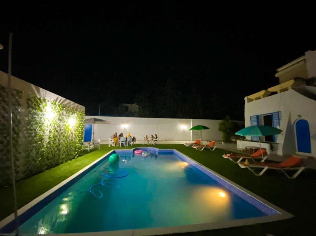 - une piscine de nuit avec des personnes à l'arrière-plan dans l'établissement Villa Sarah, à Mezraya