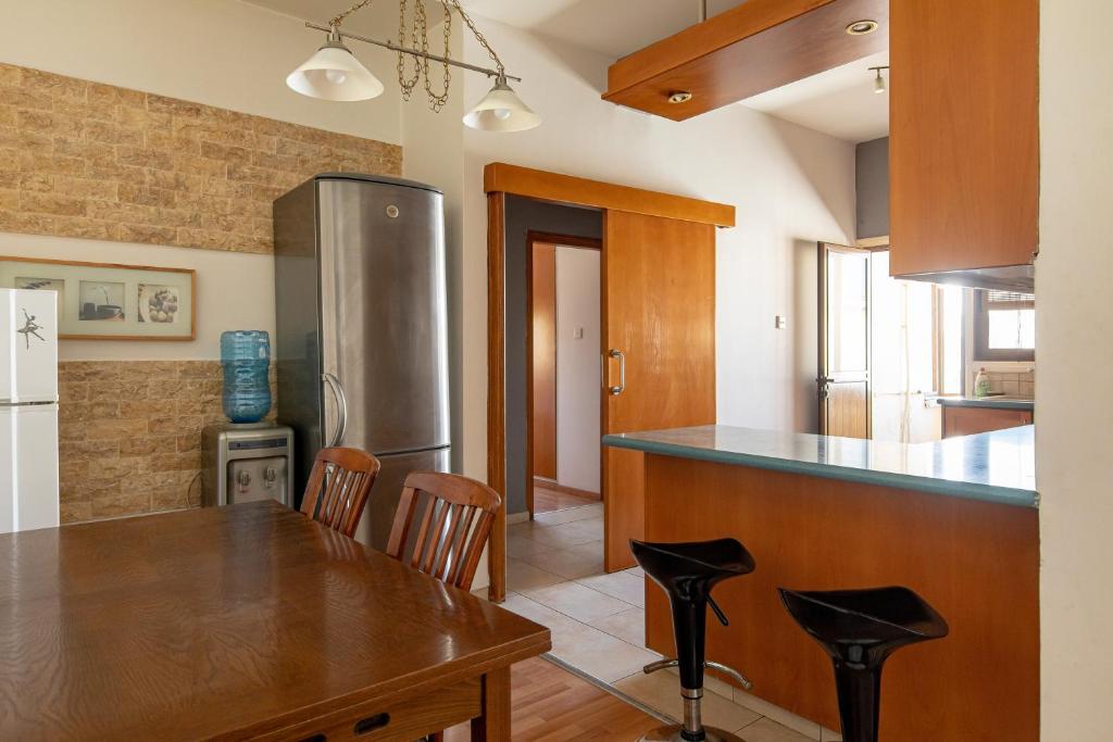 eine Küche mit einem Holztisch und einem Kühlschrank in der Unterkunft 3 bedroom Central Apartment in Larnaka