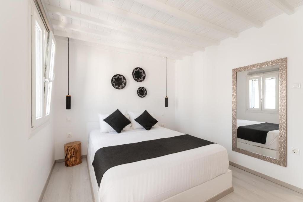 a white bedroom with a bed and a mirror at Anamnisi Mykonos in Mýkonos City