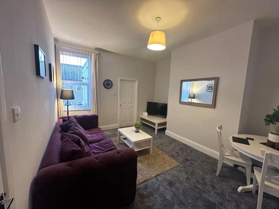 a living room with a purple couch and a table at Hambledon-Downstairs 2Bed flat in Blythe