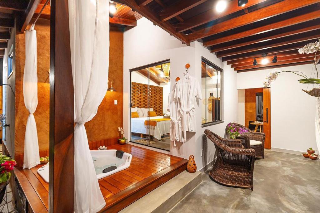 a bathroom with a tub and a bedroom with a bed at Bangalô do Sol in Pirenópolis