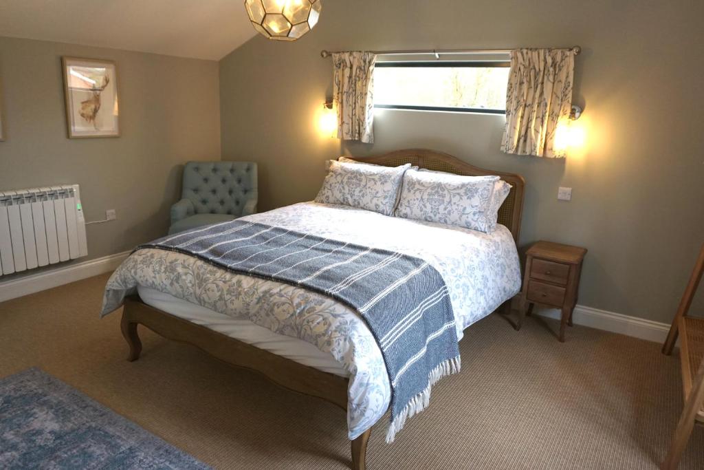 a bedroom with a bed and a chair and a window at The Cabin at the Croft - Luxury rural retreat perfect for couples in Leigh