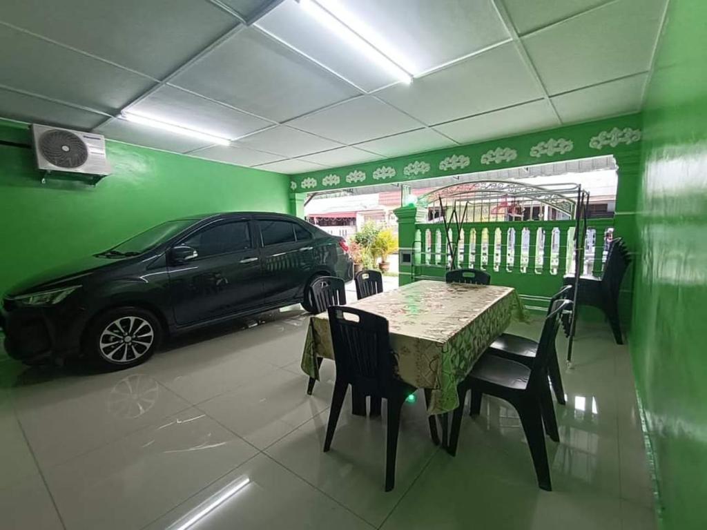 une voiture garée dans un garage avec une table et des chaises dans l'établissement Aziz homestay, à Gemencheh