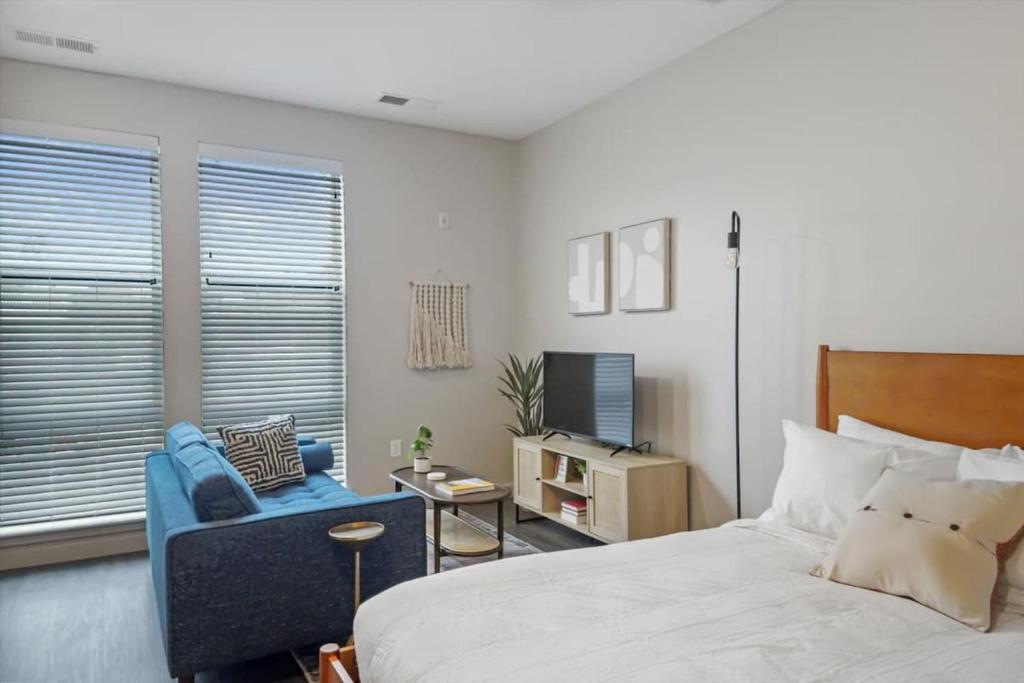 a bedroom with a bed and a chair and a television at CozySuites Modern SDO, Lawrenceville in Pittsburgh