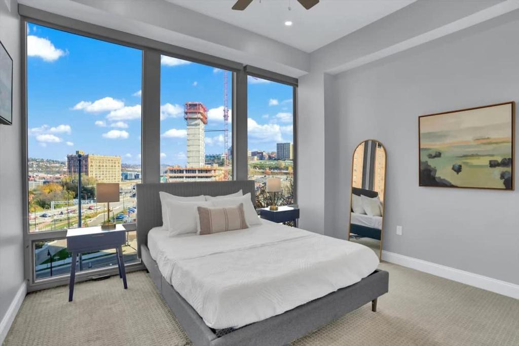 a bedroom with a white bed and large windows at CozySuites Spacious 2BR, PPG Paints Arena, Pitts in Pittsburgh