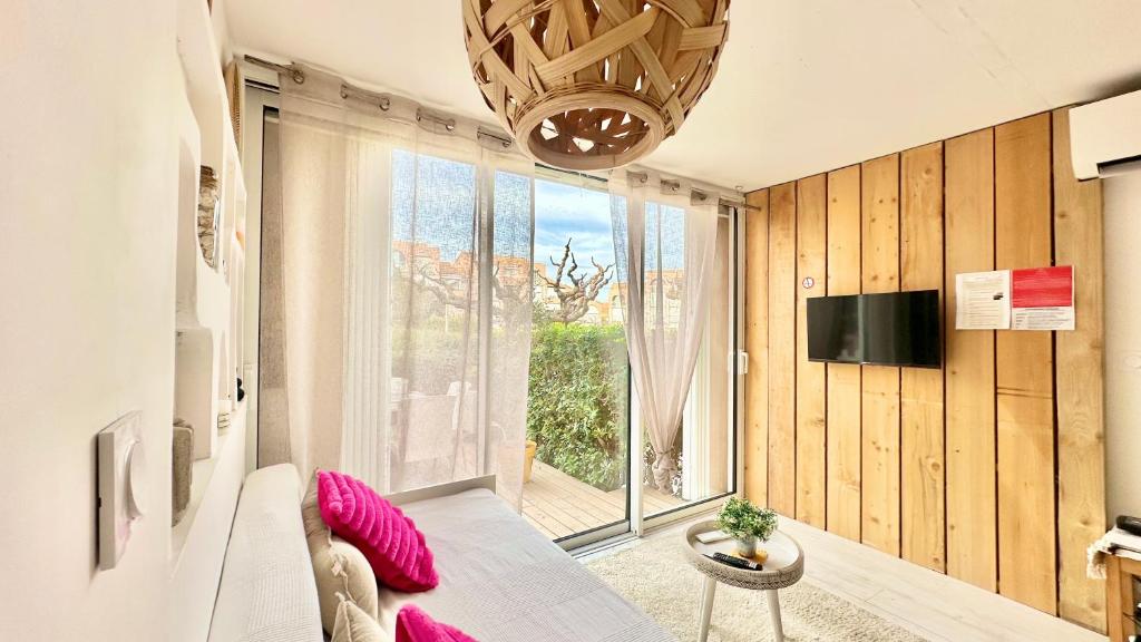 uma sala de estar com um sofá e uma grande janela em Appartement * Palavas-les-flots * Piscine em Palavas-les-Flots