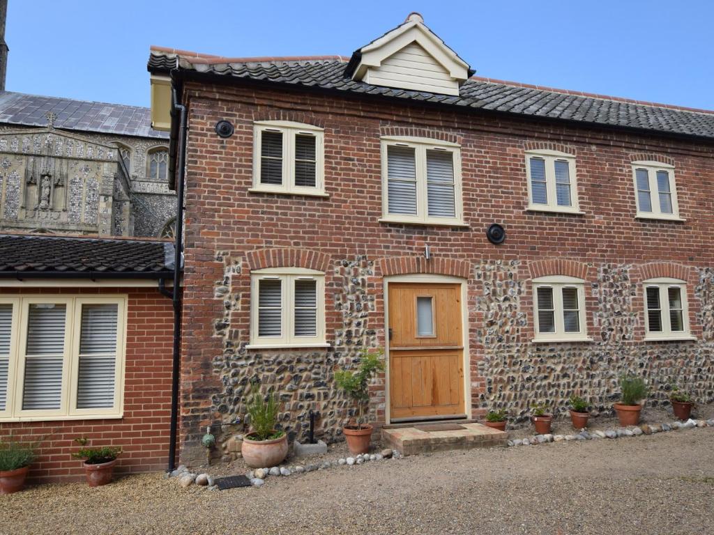 a brick house with a wooden door and potted plants at 2 Bed in Wroxham 29570 in Worstead