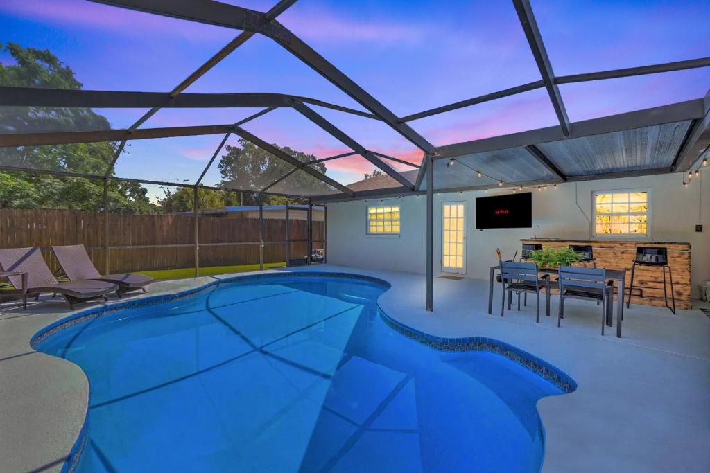 a patio with a swimming pool and a tv at Backyard Oasis! 2 mi to Pier with Pool, Patio Bar & Putting Green in Safety Harbor