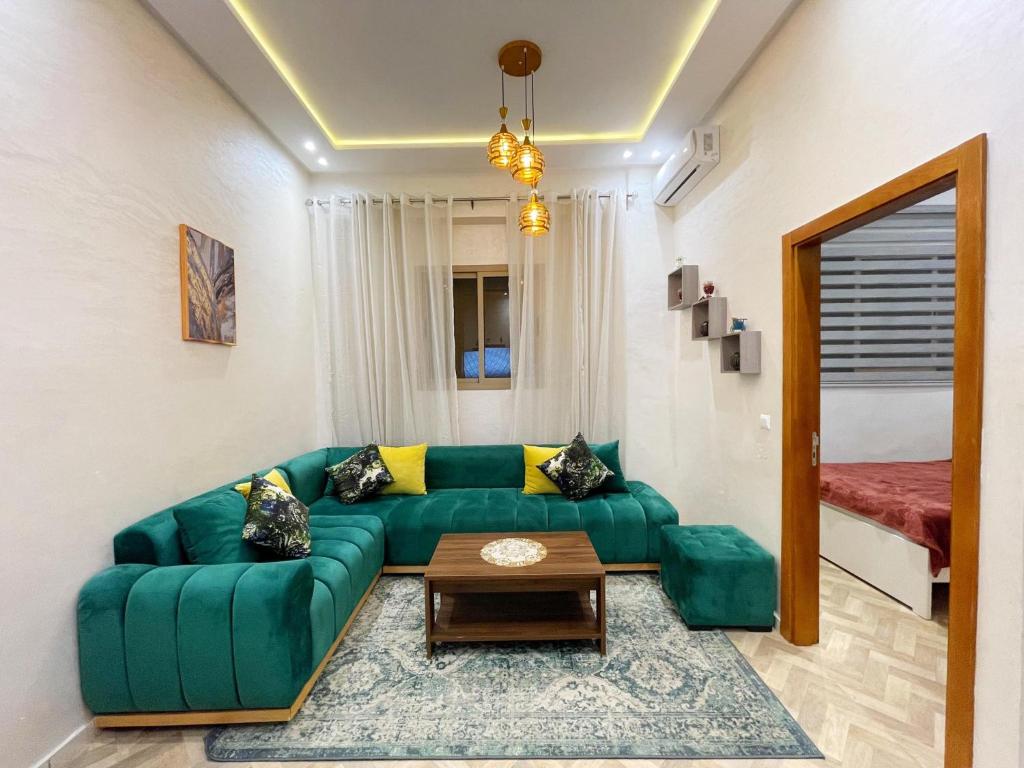 ein Wohnzimmer mit einem grünen Sofa und einem Tisch in der Unterkunft Appartement de Luxe in Kenitra