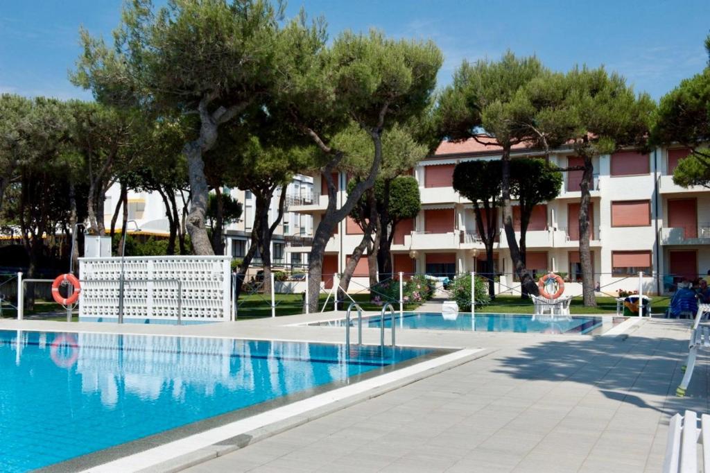 een zwembad voor een gebouw met bomen bij Park Residence 1 - Home Immobiliare in Lido di Jesolo