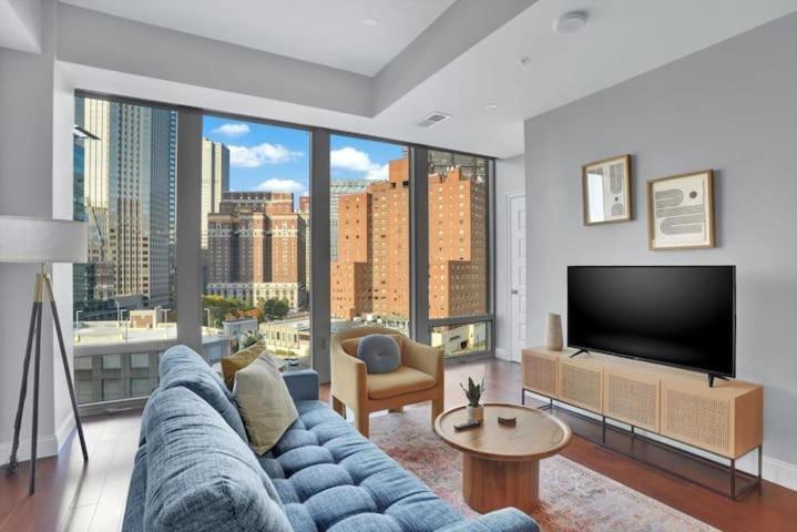 a living room with a blue couch and a large window at TWO Posh CozySuites, PPG Paints Arena, Pitts in Pittsburgh