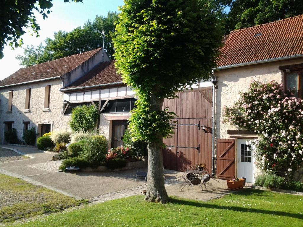 une maison avec un arbre dans la cour avant dans l'établissement La Ferme de Vintué, à Étréchy