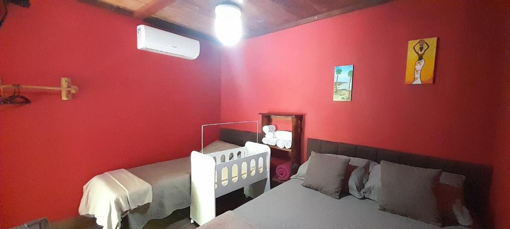 Dormitorio rojo con cama y espejo en Chalés Guigó-Cumuruxatiba, en Cumuruxatiba