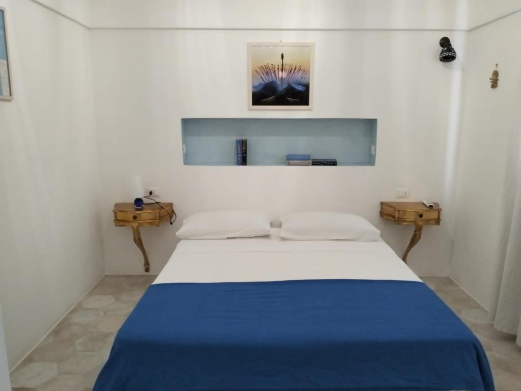 biały pokój z łóżkiem z niebieskim kocem w obiekcie Dammusielenas w mieście Pantelleria