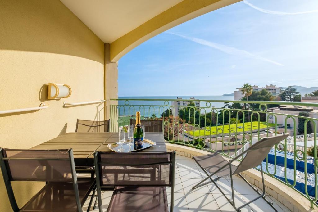 einen Balkon mit einem Tisch und einer Flasche Wein in der Unterkunft Sur la mer in Cannes