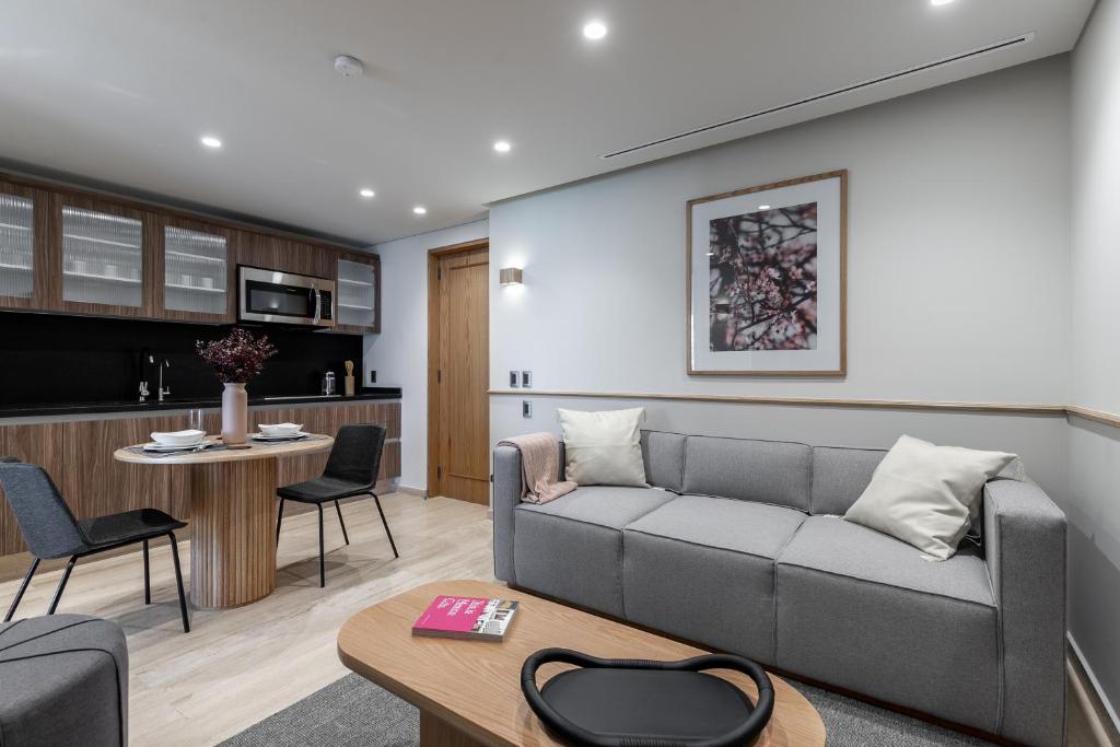 An open-plan sitting room with a sofa, dining nook and full kitchenette.