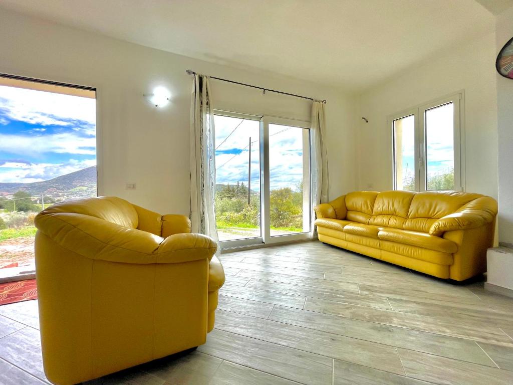 2 sofás de cuero amarillo en una sala de estar con ventanas en Green House, en Cardedu