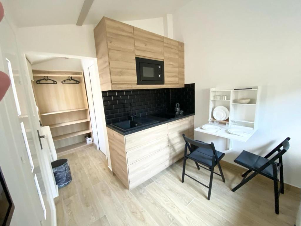 una pequeña cocina con 2 sillas negras y lavamanos en Maisonnette Cosy au calme en Gentilly