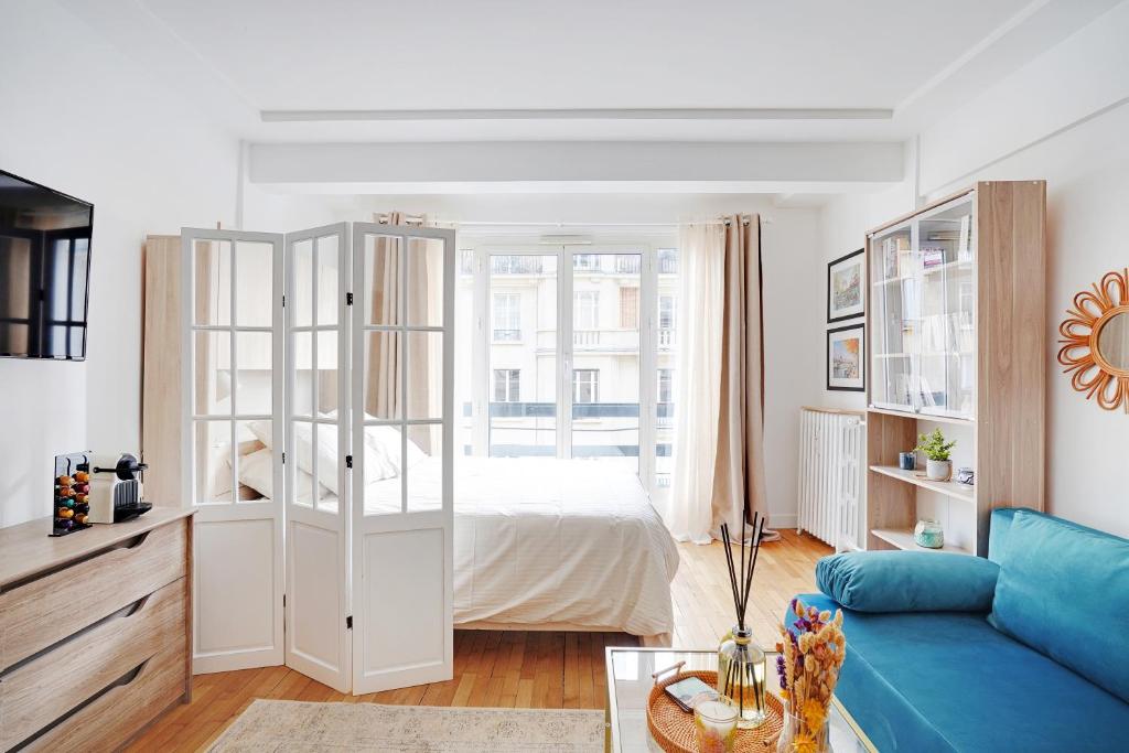 a white bedroom with a bed and a blue couch at Parisian Charm Porte Maillot in Paris
