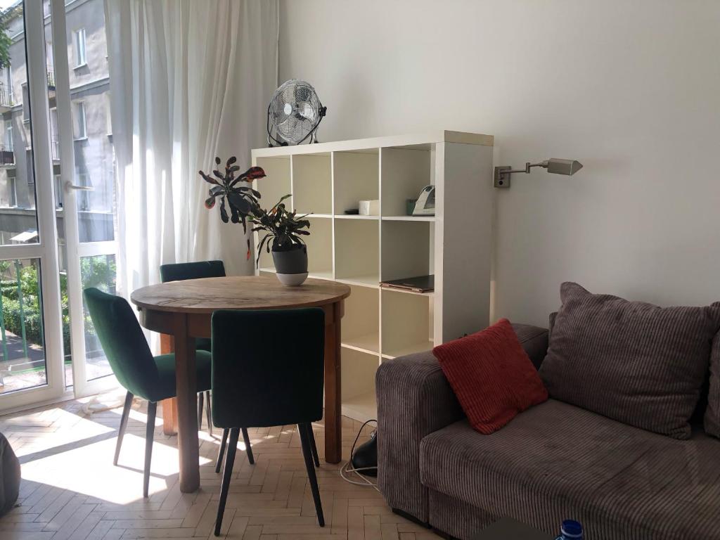 Ciche mieszkanie z balkonem في وارسو: غرفة معيشة مع طاولة وأريكة