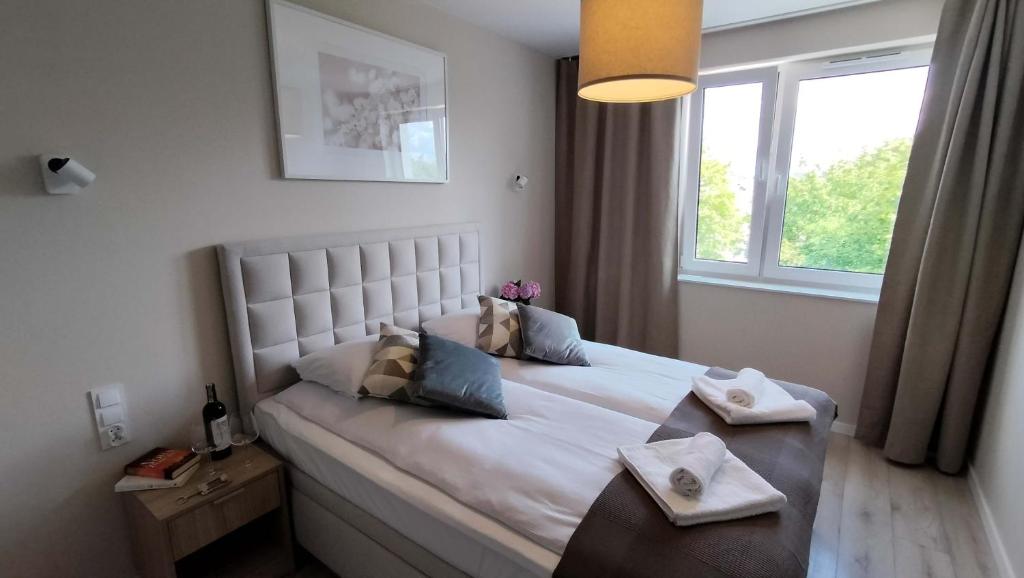 a bedroom with a large white bed with a window at Cicha Przystań Apartamenty WhiteBlue sauna&fitness&parking in Kołobrzeg