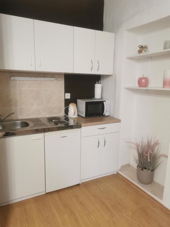 kuchnia z białymi szafkami i mikrofalówką w obiekcie Apartment Matovina w mieście Zadar