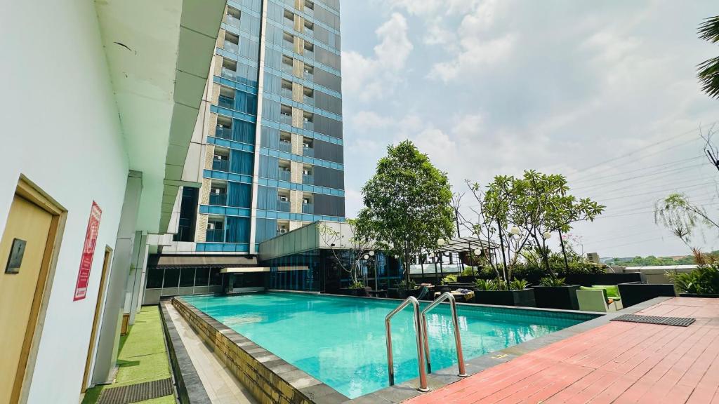 a swimming pool in front of a tall building at Tamansari Hive Cawang by Villaloka in Jakarta