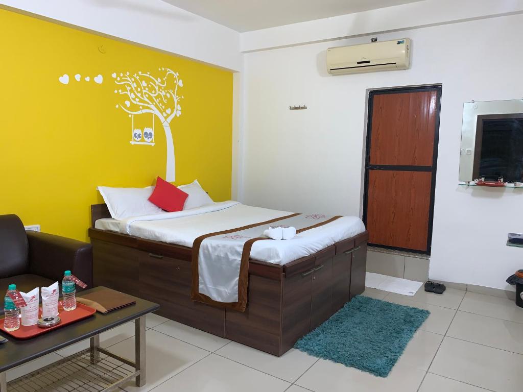 a bedroom with a bed with a tree painted on the wall at JK Rooms 147 Lions - Koradi Nagpur in Nagpur