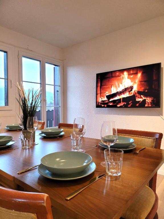 einen Esstisch mit Gläsern und einen Kamin in der Unterkunft Chalet Nature Park "Apartment Spiez" in Thun