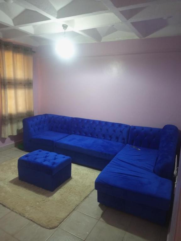 a blue couch and ottoman in a living room at Verona Apartments in Thika