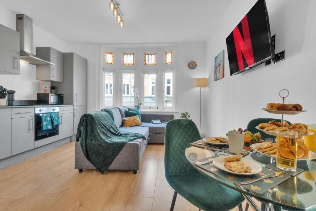 homely - West London Apartments Putney في لندن: مطبخ وغرفة معيشة مع طاولة وكراسي