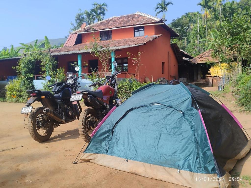 a tent and two motorcycles parked in front of a house at Kyathanamakki Base Camp Stay in Kalasa