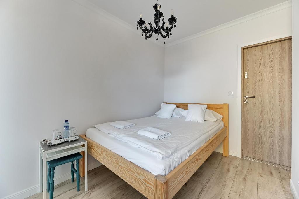 a bedroom with a bed and a table and a chandelier at Grobla Centre 4 by Grand Apartments in Gdańsk
