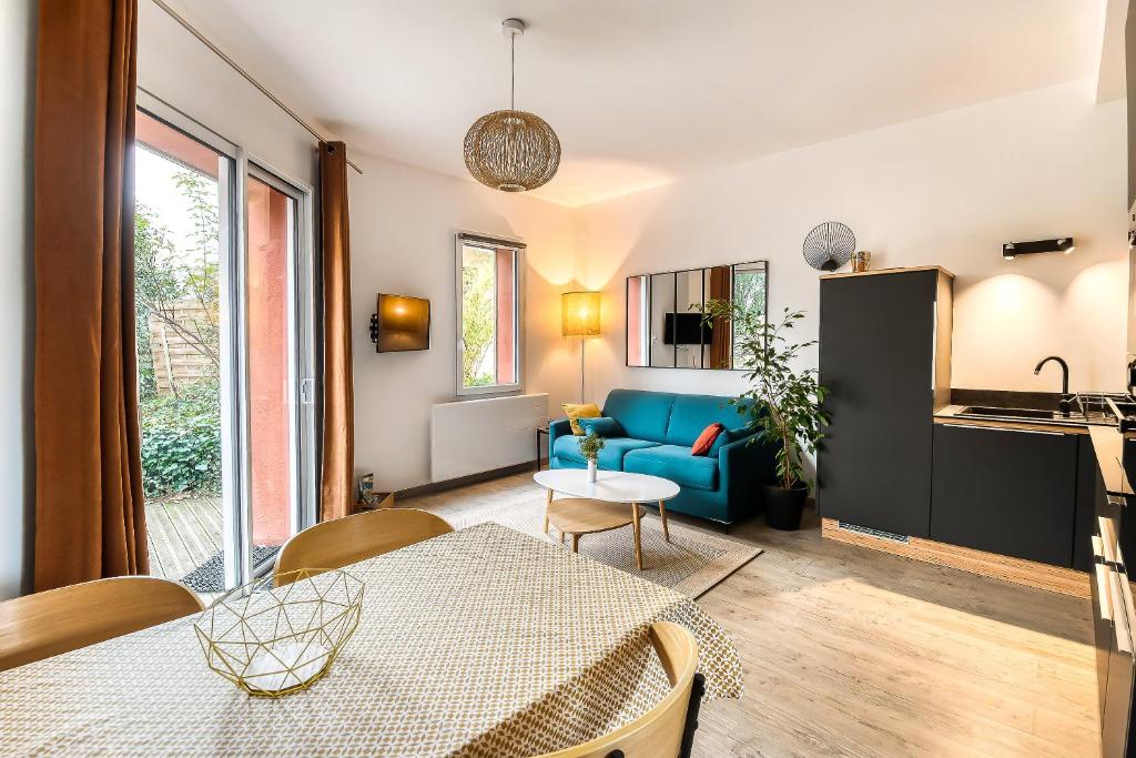 ein Wohnzimmer mit einem Tisch und einem blauen Sofa in der Unterkunft Gîte T2 A l'orée d'Angers in Avrillé