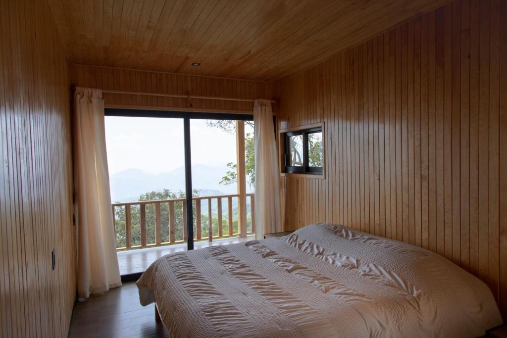 a bedroom with a bed and a large window at Cabañas Casa de Niebla in Pluma Hidalgo