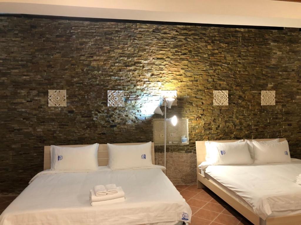 1 dormitorio con 2 camas y pared de ladrillo en Bright Starry Hostel -Vacation in Donggang, en Donggang