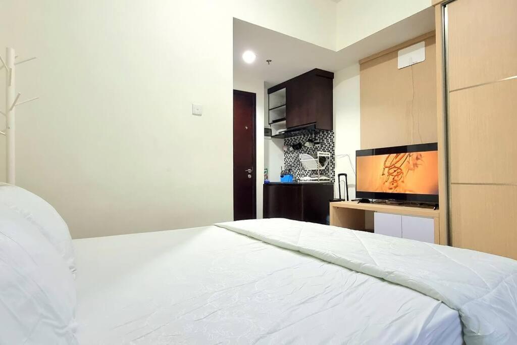 una camera con letto bianco e una cucina di Apt Grand Taman Melati 2 Studio UI Depok 5oNy with Netflix a Pondoktjina 1