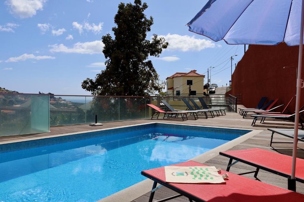 a swimming pool with two chairs and an umbrella at Villas Quinta da Lapa by AnaLodges in Câmara de Lobos
