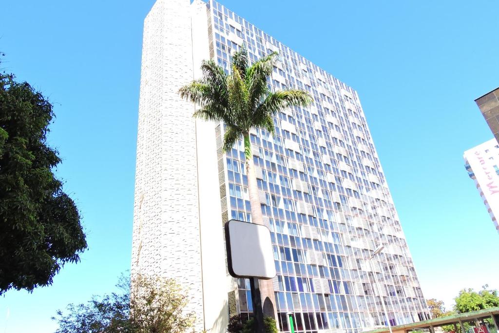 a tall building with a palm tree in front of it at Airam Brasília Hotel in Brasília